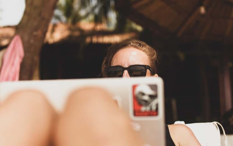 A woman uses her laptop on what appears to be the beach.