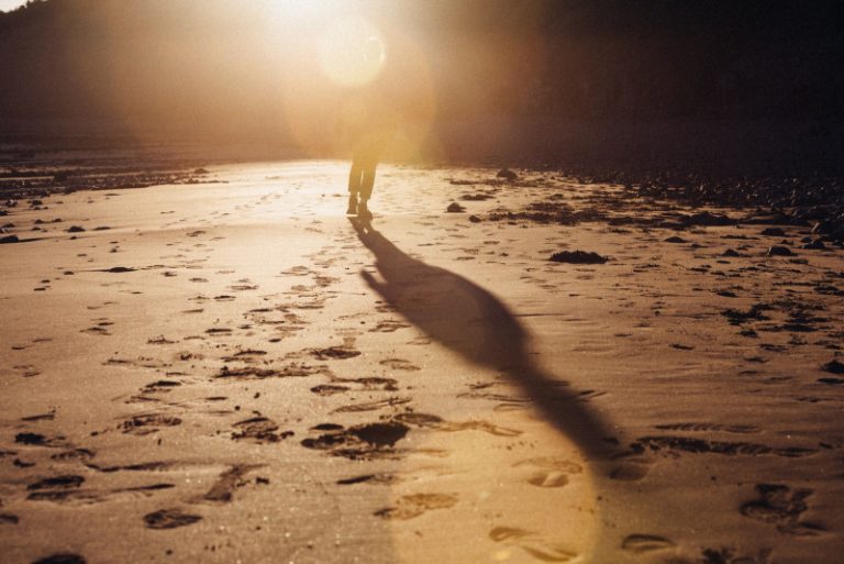 Empreintes dans le sable d'une personne qui marche au loin.