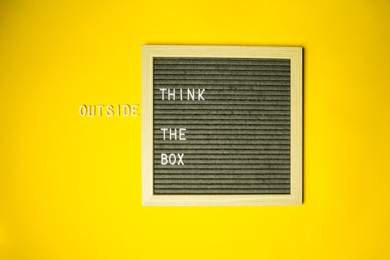 Mur jaune avec un panneau vintage disant "think out of the box".